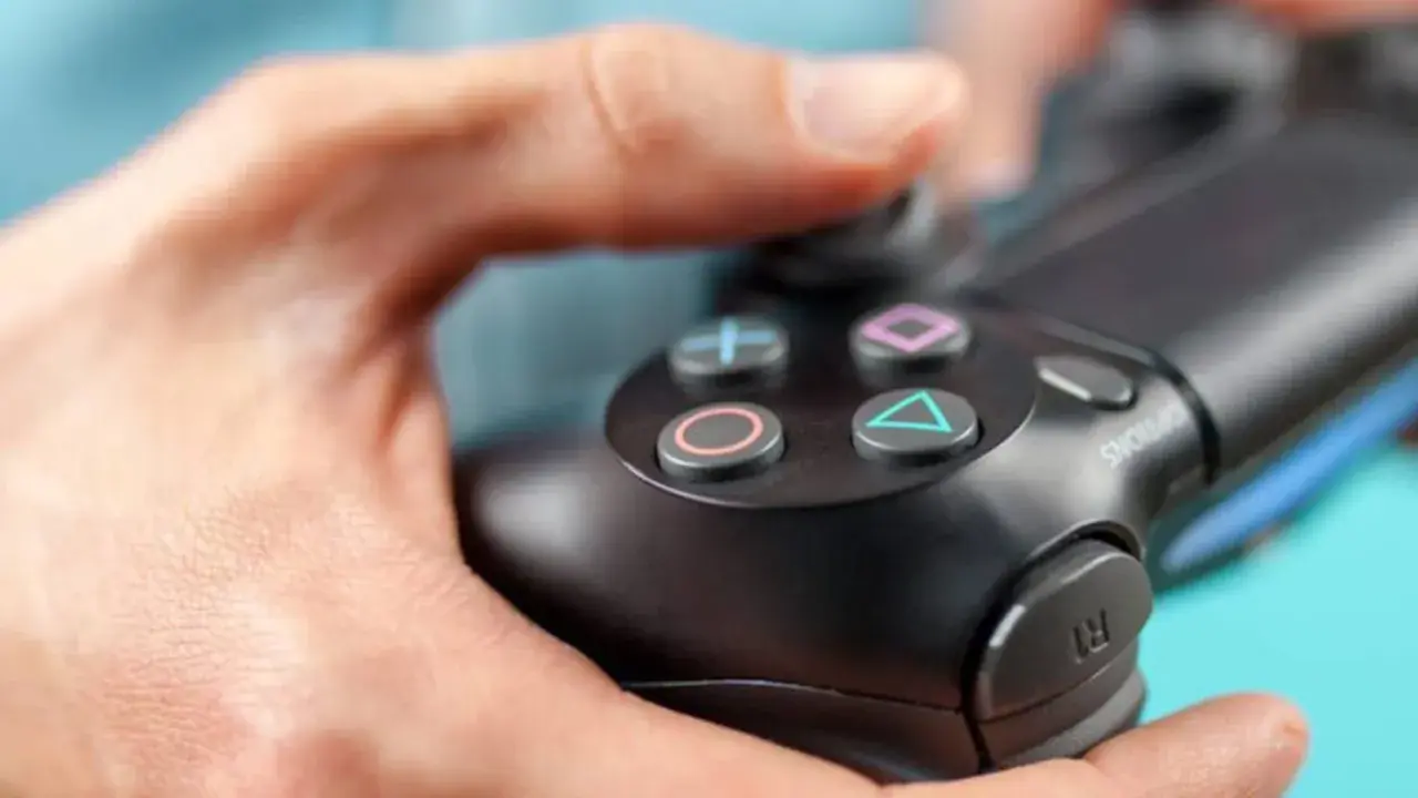 Manos sujetando un mando de PS4, con enfoque en los botones.