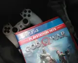 Dos mandos de PS4 y la carátula del juego "God of War", uno de los juegos exclusivos de PS4 más aclamados.