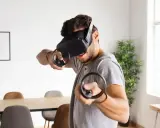 Hombre con casco de RV, inmerso en uno de los mejores juegos VR, con mandos en mano.