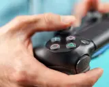 Manos sujetando un mando de PS4, con enfoque en los botones.