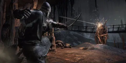 Un guerrero con armadura dispara una flecha a un monstruo en una cueva oscura. ¿Cumplen los requisitos de Dark Souls 3?