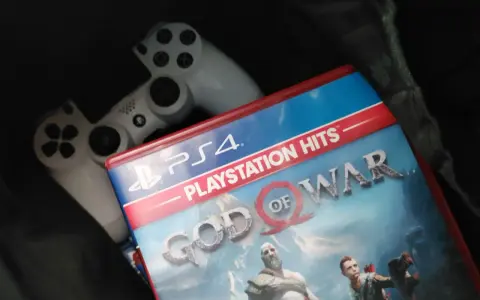 Dos mandos de PS4 y la carátula del juego "God of War", uno de los juegos exclusivos de PS4 más aclamados.