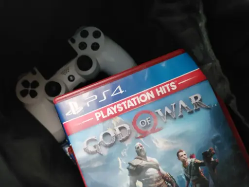 Dos mandos de PS4 y la carátula del juego "God of War", uno de los juegos exclusivos de PS4 más aclamados.