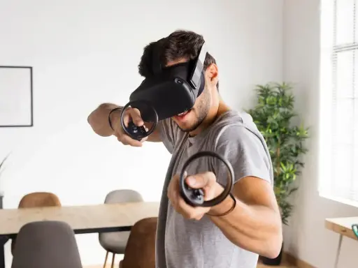 Hombre con casco de RV, inmerso en uno de los mejores juegos VR, con mandos en mano.