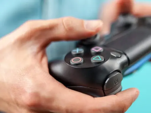 Manos sujetando un mando de PS4, con enfoque en los botones.