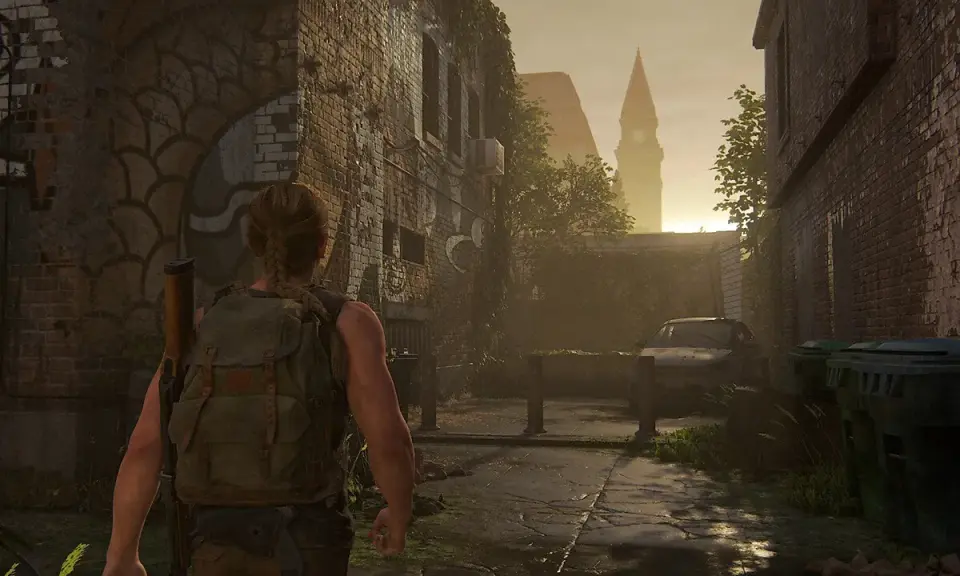 Abby camina por una calle desolada, reflexionando sobre cuanto dura The Last of Us 2. El sol se pone tras una torre.