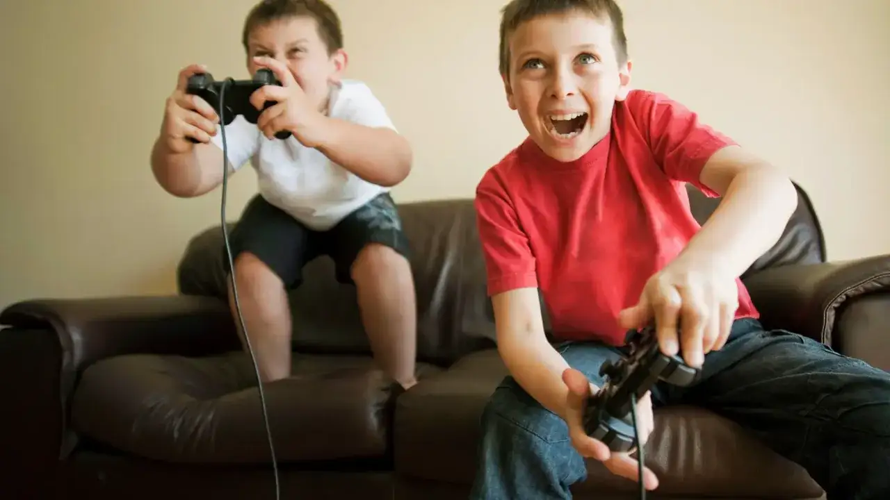 Dos ni&ntilde;os emocionados jugando videojuegos en PS4. &iexcl;Diversi&oacute;n garantizada con estos juegos ps4 para ni&ntilde;os!