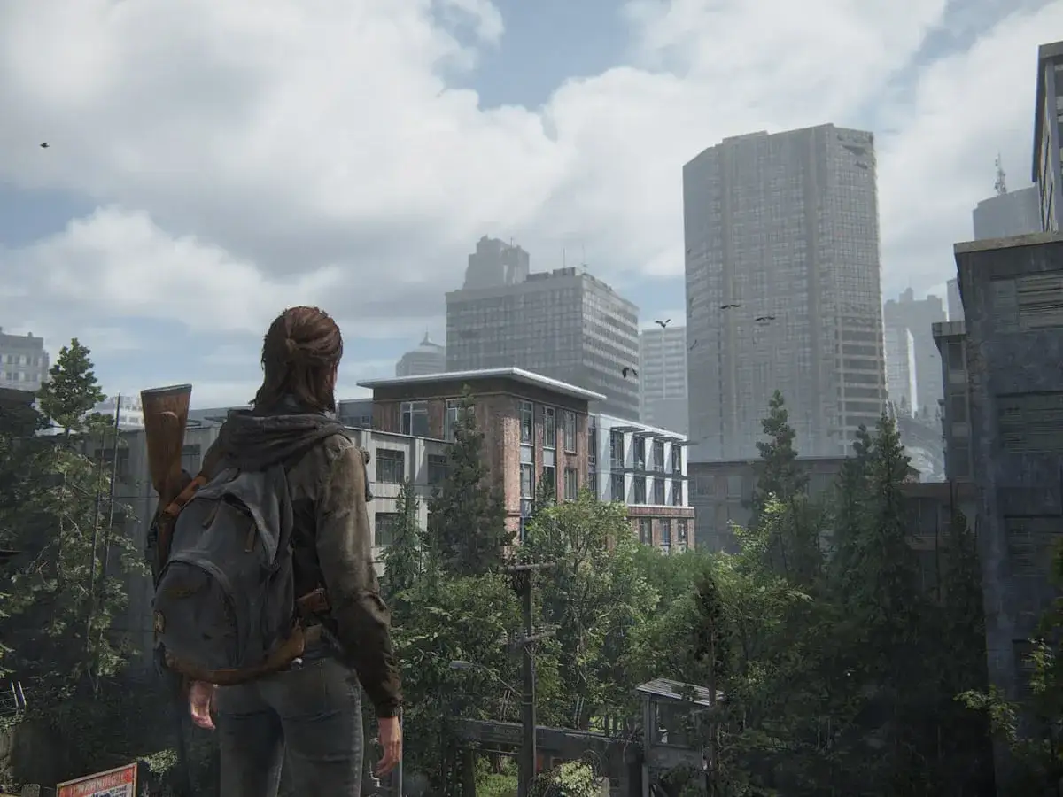 Ellie, con su mochila y rifle, observa una ciudad post-apocal&iacute;ptica en The Last of Us 2 Remastered.