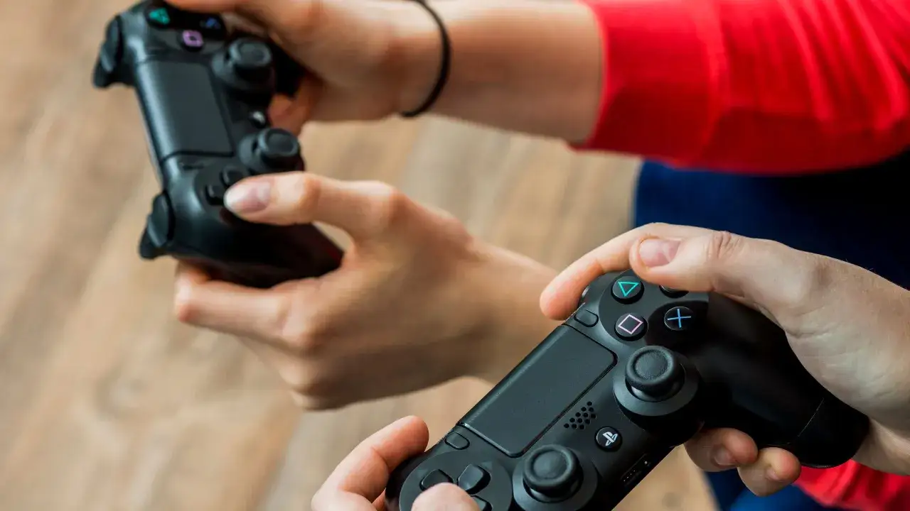 Dos personas listas para compartir juegos PS4, cada una sosteniendo un mando DualShock 4.
